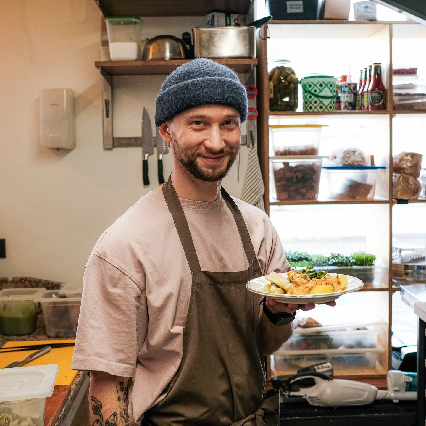 Pavārs ar šķīvi saspaidīta tofu mērces ar kartupeļiem